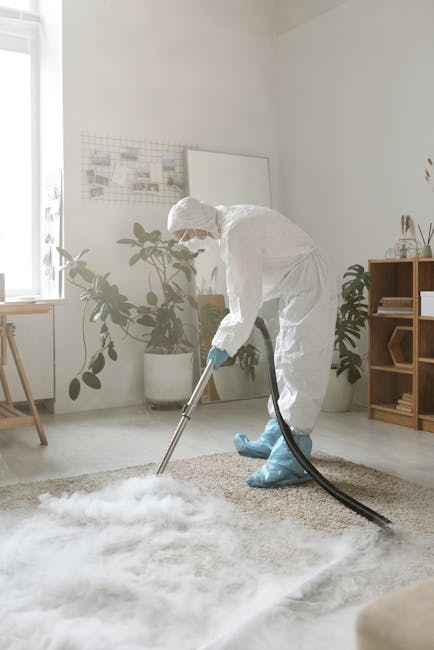 A woman uses a yellow vacuum cleaner to deep clean a patterned beige and green rug in a living room, which has wooden flooring and a brown leather sofa. The room is well-lit, and the woman is wearing 
